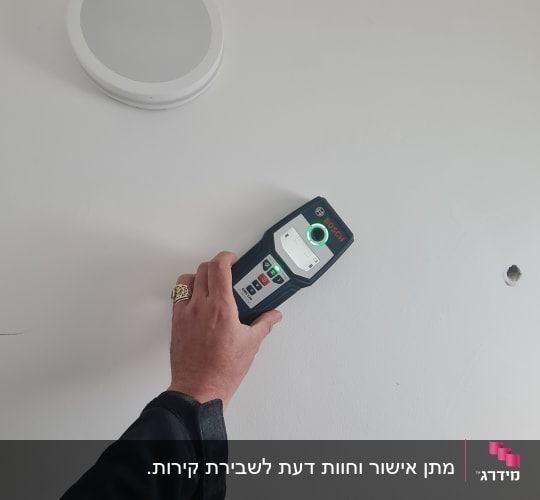 יד מחזיקה מכשיר מדידה על קיר לבן